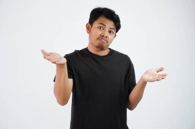 Handsome young asian man wearing black t shirt show hands up confused i don't know isolated on white background