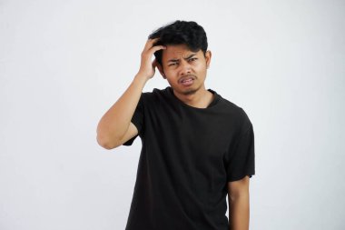 confused young asian man holding head wearing black t shirt isolated on white background