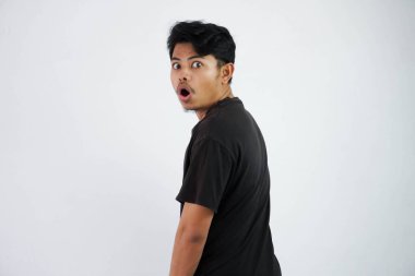 shocked Asian young man black t shirt open mouth feels amazed turn back to looking camera isolated on white background