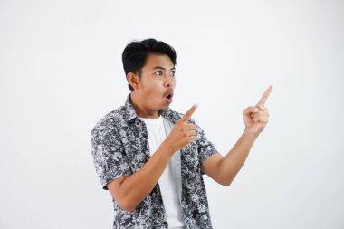 shocked asian man with fingers pointing to the side wearing black shirt isolated on white background