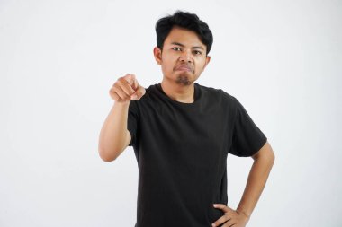 angry asian man with finger pointing forward. Portrait of young man pointing index finger at camera, standing over white background.