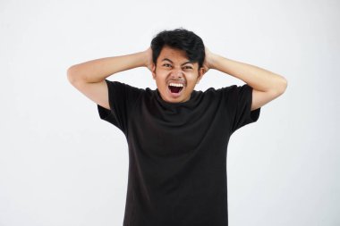shouted or shocked young asian man holding head with mouth open wearing black t shirt isolated