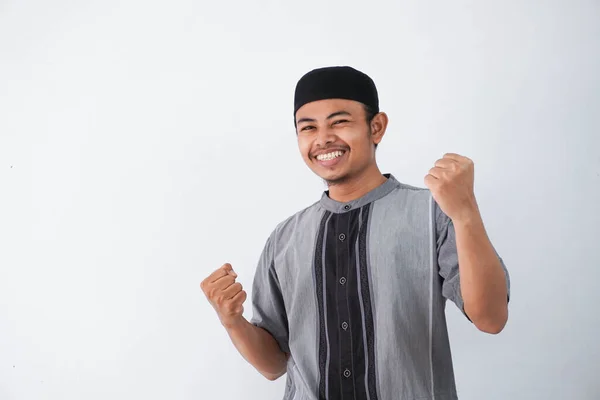 成功した幸せな若いアジアのイスラム教徒の男叫びとショー勝利ジェスチャー身に着けています灰色のイスラム教徒の服白い背景に隔離 — ストック写真
