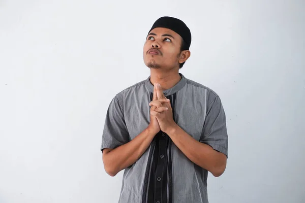 thinking young asian muslim man looking up thinking gesture, looking for idea wearing grey muslim clothes isolated on white background