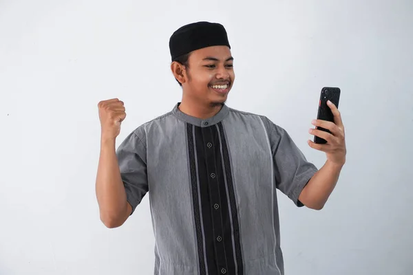 Улыбающийся Счастливый Молодой Азиат Мусульманин Держит Смартфон Кулаком Руке Делая — стоковое фото