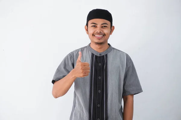 笑顔や幸せな若いイスラム教徒の男を示す手親指アップ白い背景に隔離された灰色のイスラム教徒の服を着て — ストック写真
