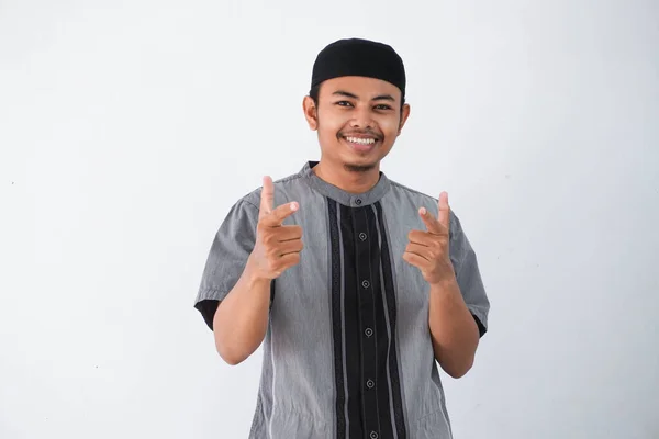 若いアジア系イスラム教徒の男性の笑顔が両手の指を白い背景に孤立した灰色のイスラム教徒の服を着てカメラに向け — ストック写真