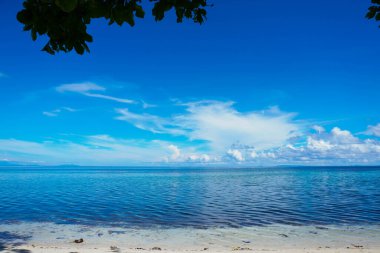 Arkaplan olarak parlak mavi gökyüzü olan açık denizin genişliği