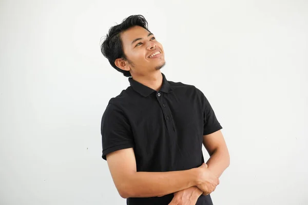 年轻的亚裔男子轻松而快乐的笑着 脖子伸展 露出牙齿 身穿黑色马球T恤 背景呈白色 — 图库照片