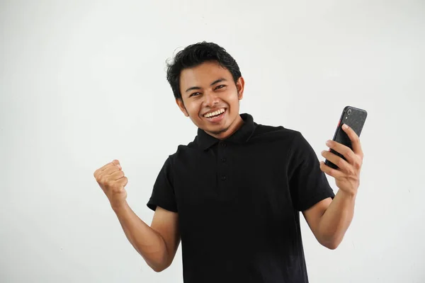 エキサイティングな幸せな若いアジア人男性は スマートフォン勝利宝くじゲームを使用して喜びを感じます モバイルアプリメッセージでキャッシュバックのオンラインギフトを得る ホワイトバックグラウンドで隔離された携帯電話を保持 — ストック写真