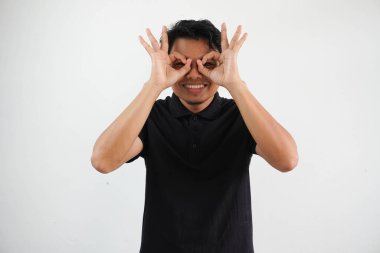 Asyalı genç adam heyecanlı. Gözünü ayırmıyor. Siyah polo tişört giyiyor.