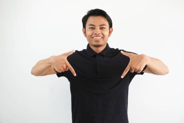 Genç Asyalı adam kameraya gülümsüyor ve beyaz arka planda siyah polo tişört giyiyor..