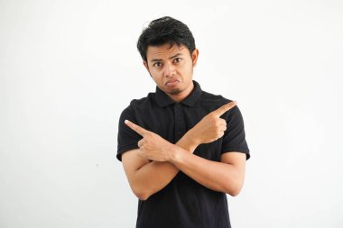 Siyah polo giyen genç Asyalı adam, beyaz stüdyo iki seçenek arasında seçim yapmaya çalışıyor..