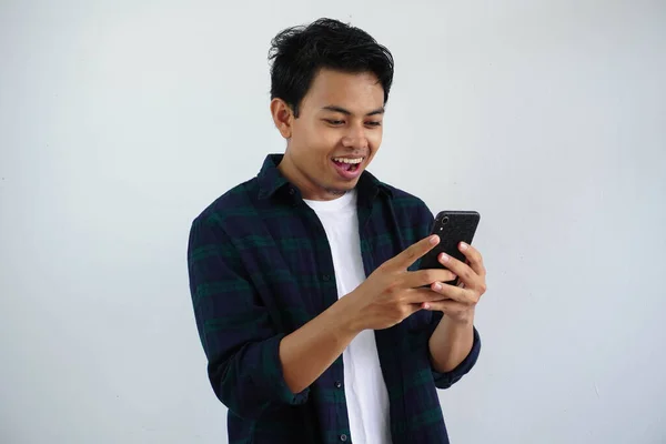 stock image smiling young asian man looking to his mobile phone with happy expression isolated on white background