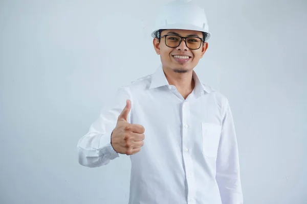 年轻的亚洲建筑师 戴着建筑商安全帽 带着孤独的背景 手举着快乐的大拇指 在镜头前看着成功的表情 — 图库照片