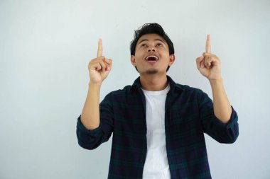 Asyalı genç adam heyecanlı bir ifade sergiliyor ve iki elini de beyaz arka planda izole bir şekilde havaya kaldırıyor.