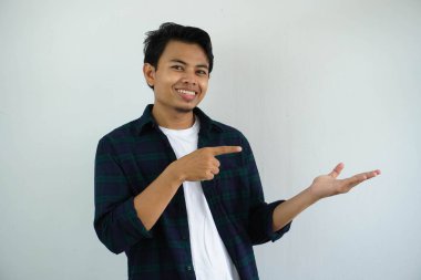 Gülümseyen Asyalı genç adam avucunu açık tutarken beyaz arka planda izole edilmiş.