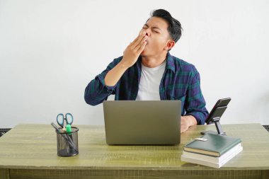 Genç Asyalı serbest çalışan, beyaz arka planda elleri kapalı esniyor.