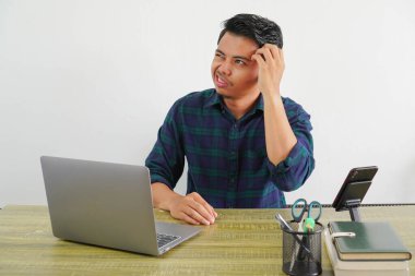 preoccupied pensive young asian man sit work at wooden desk with pc laptop. Achievement business career lifestyle concept. put hand on head clipart