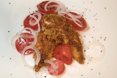 Beyaz arka planda domates ve soğanlı ev yapımı çıtır tavuk göğsü.