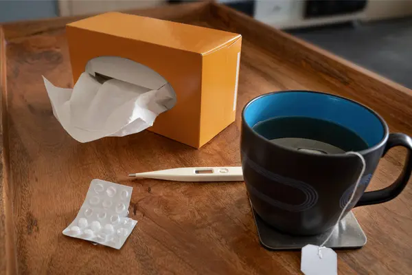 Self-help for flu infections with plenty of tea, tablets, tissues and fever thermometer