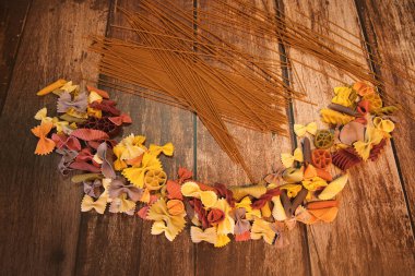 Tahta görünümlü arka planda tam tahıllı spagetti ile çeşitli renkli erişteler.