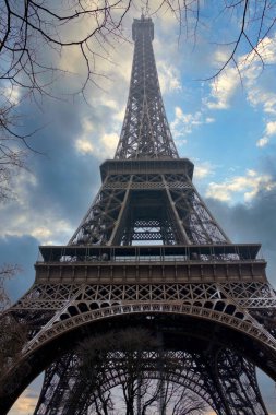 Eiffel Kulesi, bulutlu mavi gökyüzünde dallarla çevrili.