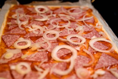 Fırında salamlı, soğanlı ve peynirli pizza.