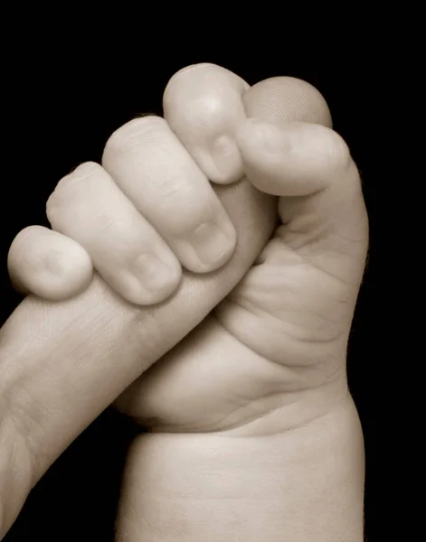 Siyah Arka Planda Bir Adamın Serçe Parmağını Tutan Bir Bebek — Stok fotoğraf