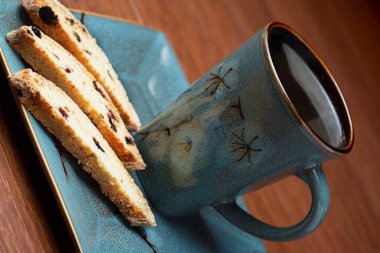 a cup of coffee with biscotti on a bark background