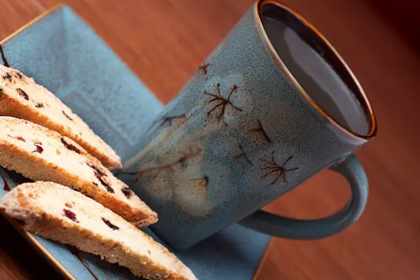 a cup of coffee with biscotti on a bark background