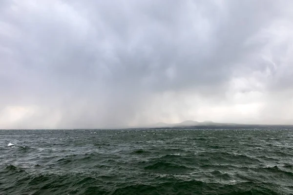 Bulutlu havada Sevan Gölü 'nde fırtına bulutları ve arka planda dağlar.