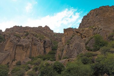 Güneşli ve bulutlu bir günde, gün batımında, altın saat boyunca Geghard manastırı yakınlarındaki Rocky ve orman dağları.