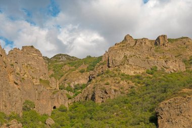 Güneşli ve bulutlu bir günde, gün batımında, altın saat boyunca Geghard manastırı yakınlarındaki Rocky ve orman dağları.