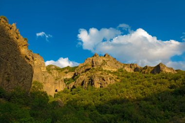 Güneşli ve bulutlu bir günde, gün batımında, altın saat boyunca Geghard manastırı yakınlarındaki Rocky ve orman dağları.