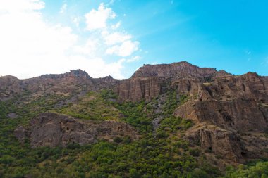 Güneşli ve bulutlu bir günde, gün batımında, altın saat boyunca Geghard manastırı yakınlarındaki Rocky ve orman dağları.