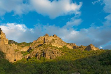 Güneşli ve bulutlu bir günde, gün batımında, altın saat boyunca Geghard manastırı yakınlarındaki Rocky ve orman dağları.