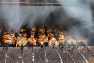 Brezilya usulü ızgarada nefis barbekü pişirme görüntüsü. Lezzetli domuz eti ve patates ızgarada kızartılıyor. Barbeküyü hazırlarken duman çıkıyor..