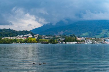 Göl ve küçük bir yerleşim yeri ve arka planda bir dağ ve bulutlarla doğal bir manzara.