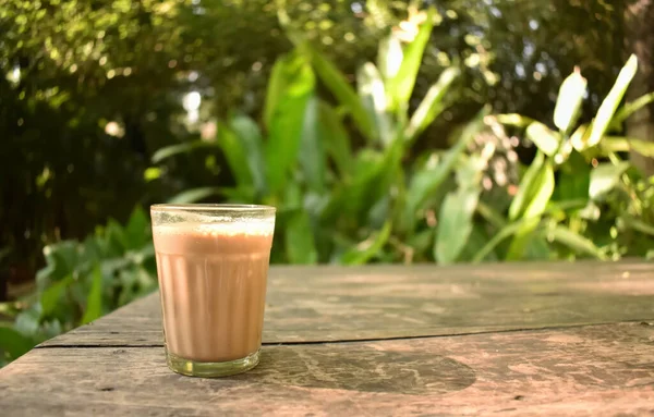 stock image A closeup selective focus picture of a tea glass on a table against a green background blurred. It is also called chai in India