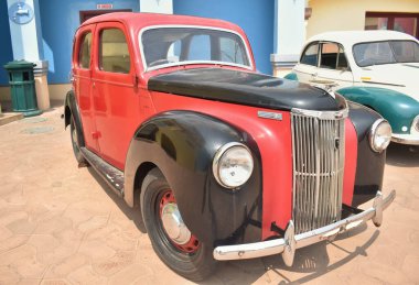 Eski moda kırmızı ve siyah renkli bir Amerikan arabası gündüz vakti dışarıda park edilmiş..