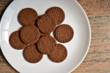 Beyaz bir tabakta çikolata renkli bisküvilerin yakın çekim resmi..