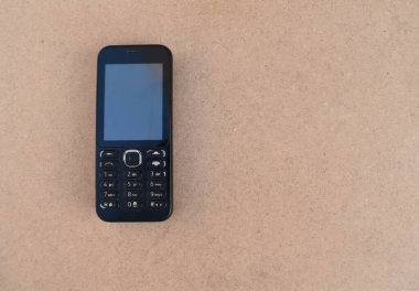Kahverengi arka planda eski bir cep telefonunun yakın plan fotoğrafı.