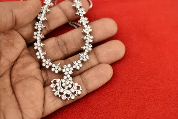 赤い背景の美しいダイヤモンドネックレスを調べる男 インドのジュエリーは有名です — ストック写真