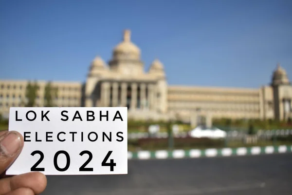 Hindistan 'daki parlamento binasının önünde 2024 Lok Sabha seçimleri yazılı bir kartın yakın plan fotoğrafı.