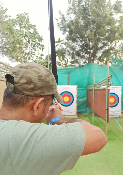 Açık alanda okuyla hedefe nişan alan bir adamın yakın plan fotoğrafı..