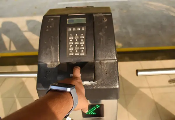 A closeup picture of a person using the attendance turnstile gate near a corporate campus parking area