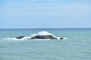 Kanyakumari, Hindistan 'da açık mavi deniz suyuyla okyanusun ortasındaki kayaya vuran bir suyun manzaralı görüntüsü.