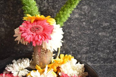 A closeup picture of colorful barberton daisy flowers with Leaves arranged in a vase. clipart