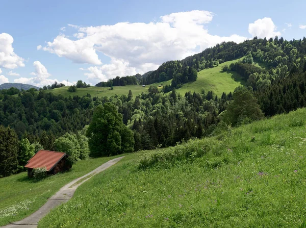 Gökyüzü mavi, bulutlar bahar zamanı, Bavyera Alpleri 'nde güzel güneşli bir günde, dağ çayırlarıyla birlikte, kayan tepelerin manzaralı manzarası..